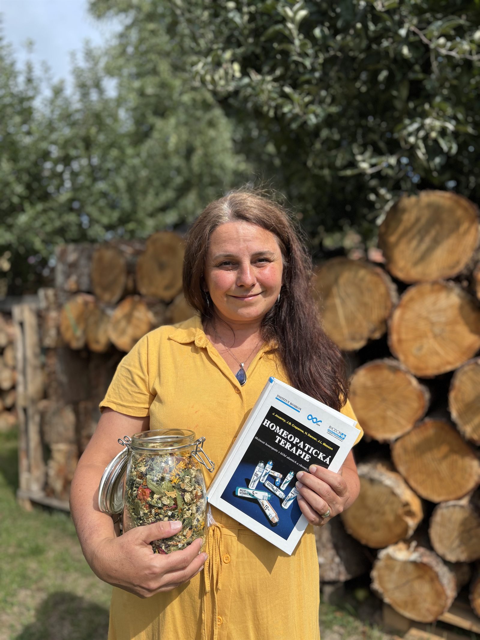 Jana Kokošková s miskou sušených bylin a knihou o homeopatii
